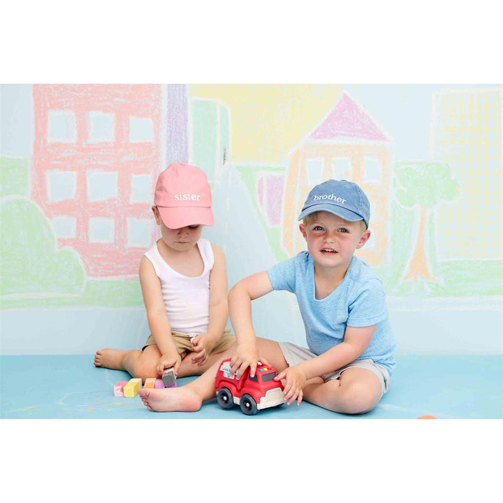 Two children playing with a toy car in front of a colorful wall.