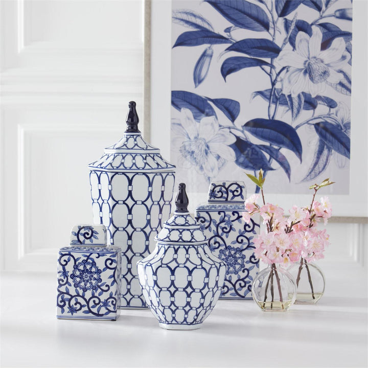 Set of blue and white decorative vases with a floral painting in the background.