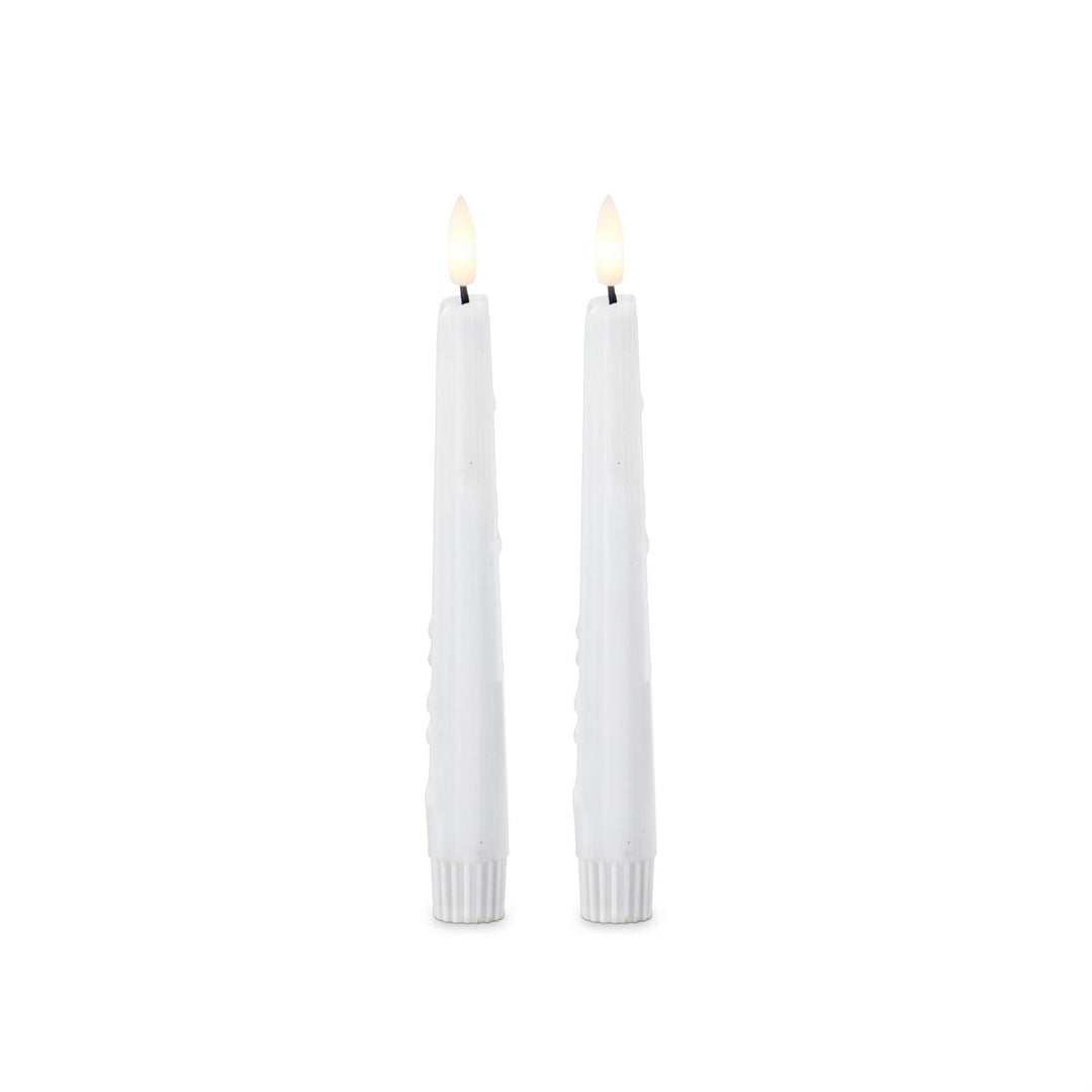 Two white candles with small flames on a white background