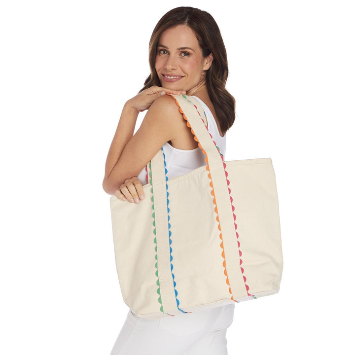 Woman holding a cream-colored tote bag with colorful stripes on a white background