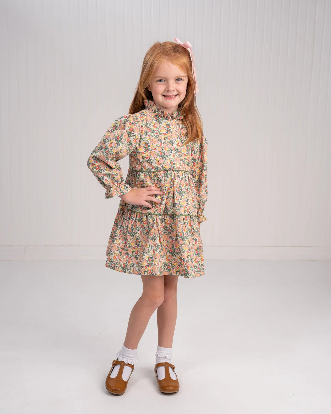 Young girl wearing a floral dress on a plain background