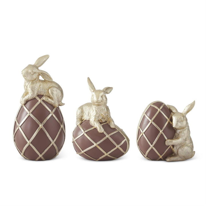 Three decorative egg-shaped figurines with rabbits on a white background