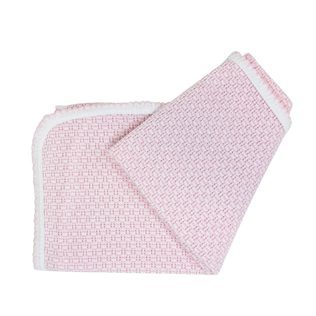 Pink textured blanket with white trim on a white background