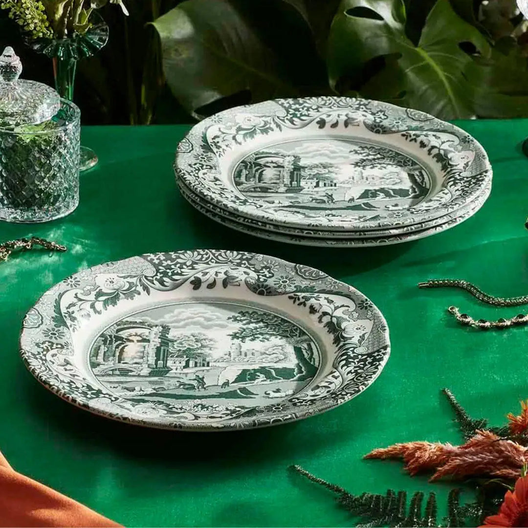 Decorative plates with black and white patterns on a green tablecloth with plants in the background