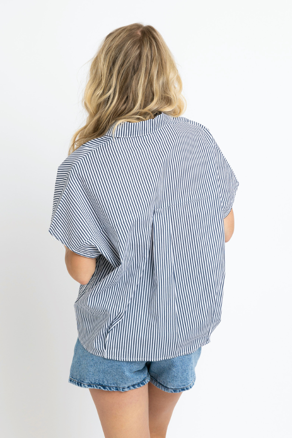 Woman wearing a blue and white striped shirt and denim shorts on a white background