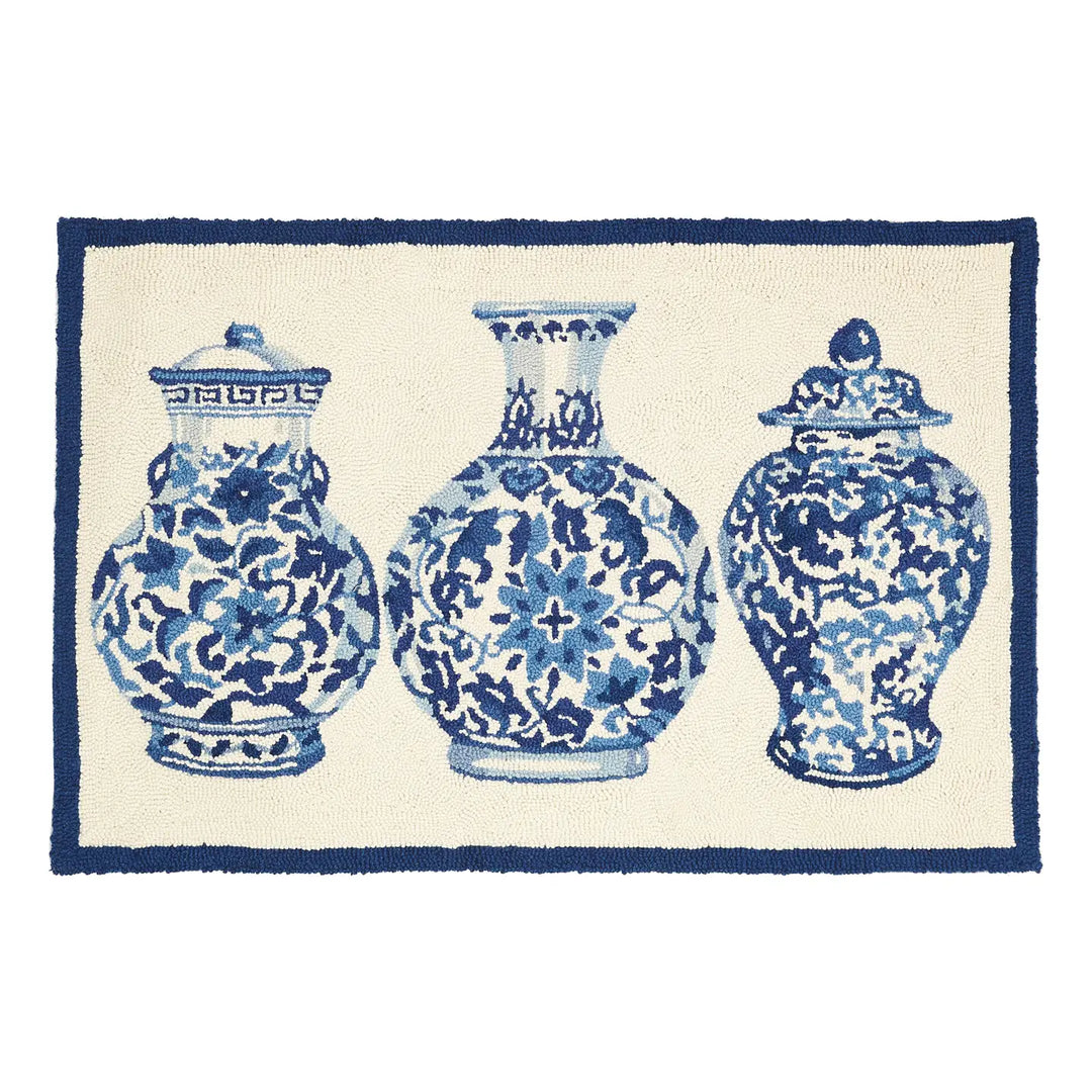 A rectangular hooked rug featuring three blue and white floral patterned vases.