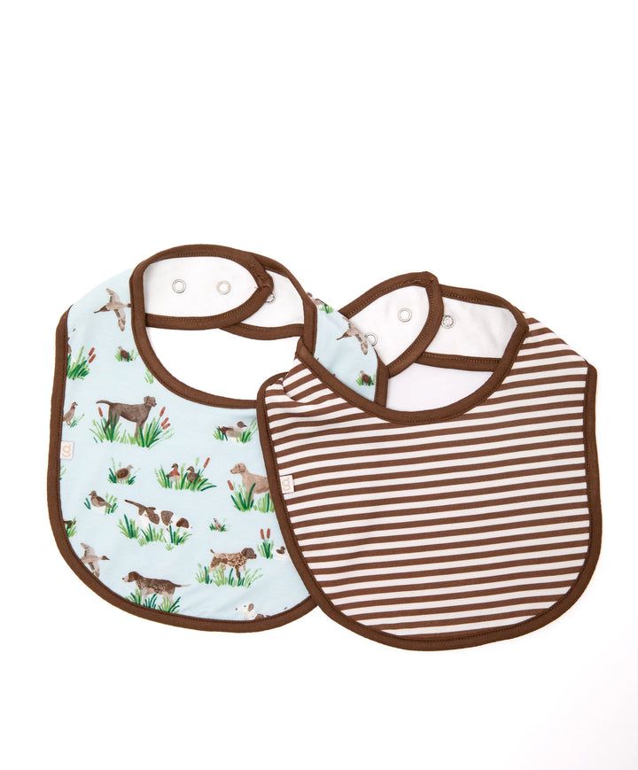 Two baby bibs with brown trim, one featuring a light blue background with a rustic hunting dog and duck print, and the other featuring brown and white horizontal stripes.