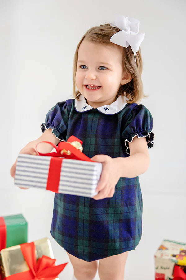 Child in a plaid dress holding a gift box with a white background