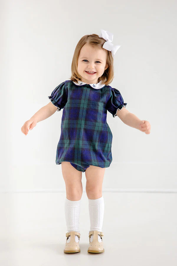 Child wearing a blue plaid dress with white collar and cuffs on a white background