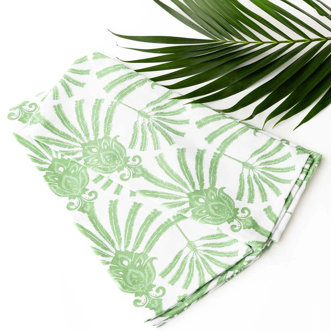 Green leaf-patterned fabric with a palm leaf on a white background