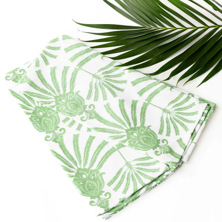 Green leaf-patterned fabric with a palm leaf on a white background