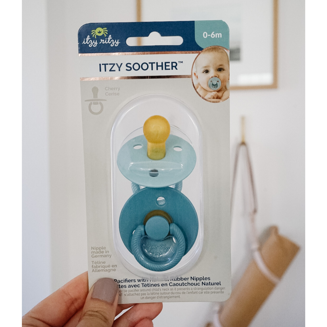Itzy Ritzy baby soother packaging held by a hand with a plain background