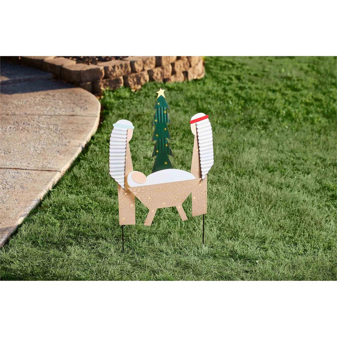 Decorative nativity scene with three wise men and a tree on grass