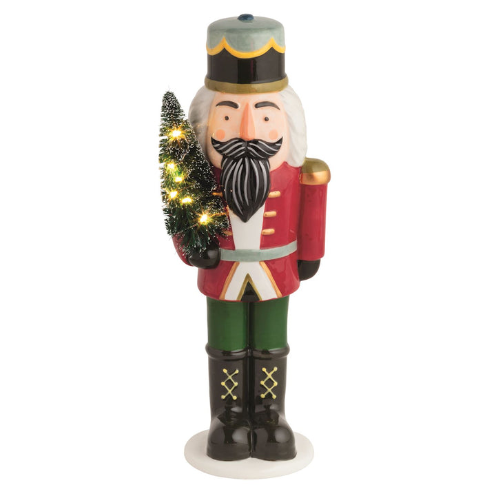 Hand-painted ceramic nutcracker holds light-up bottle brush tree. Batteries included.