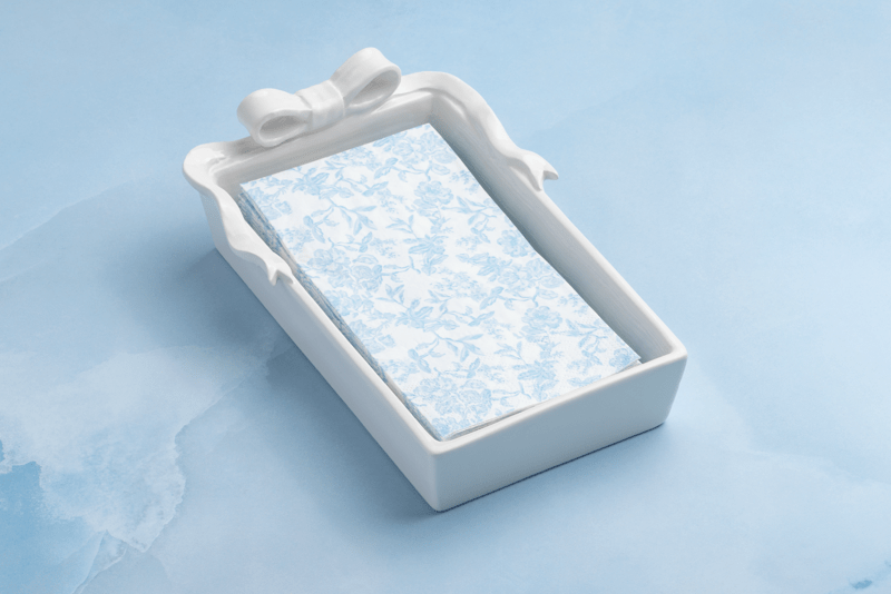 WHITE EMBOSSED BOW GUEST NAPKIN HOLDER ON BLUE TABLE