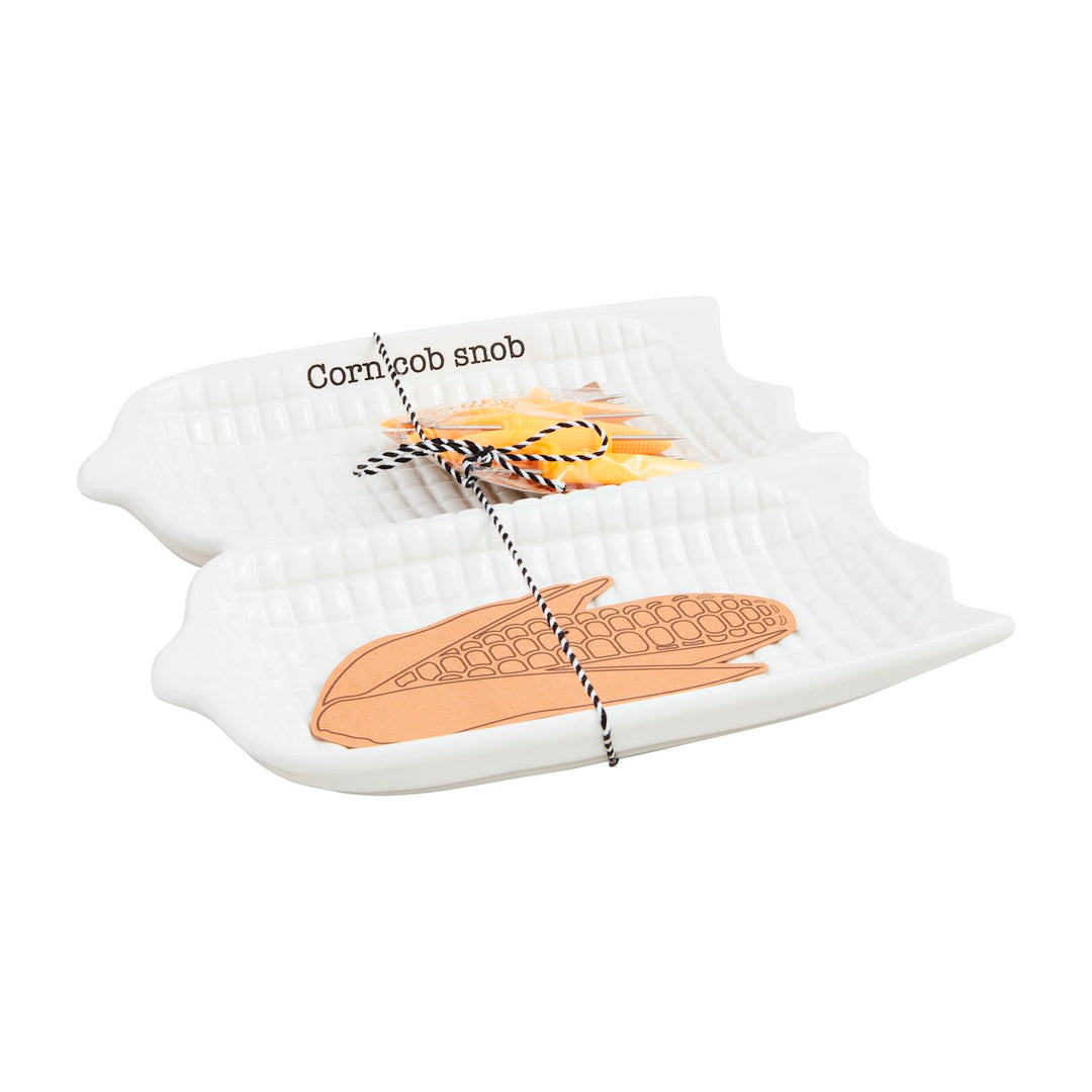 White ceramic corn-shaped serving dish set with textured detail, includes corn-themed paper goods and “Corn cob snob” accent