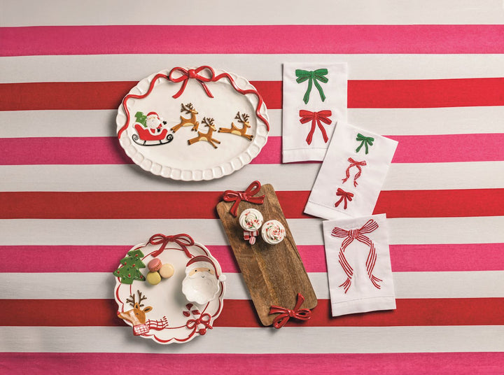 Decorative plates and towels with festive designs on a striped red and white tablecloth.