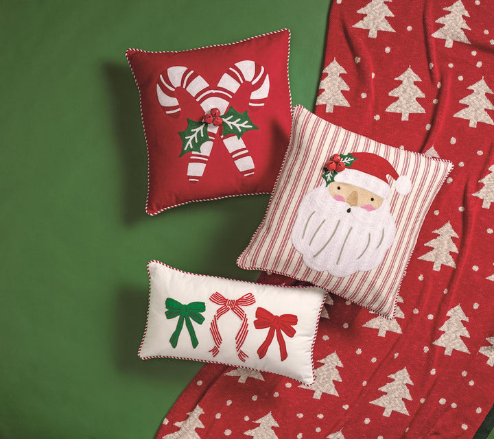 Three decorative canvas throw pillows Christmas themed on red and green backdrop
