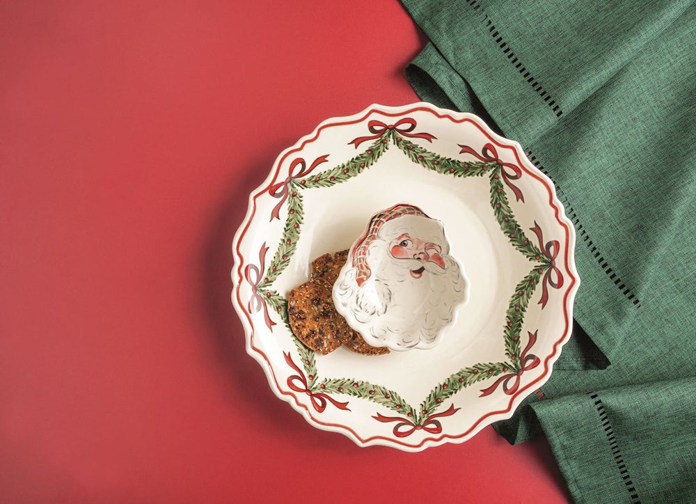 2-piece set. Stoneware chip bowl features hand-painted rim detail. Comes with coordinating Santa dip cup. Red background with green table linens