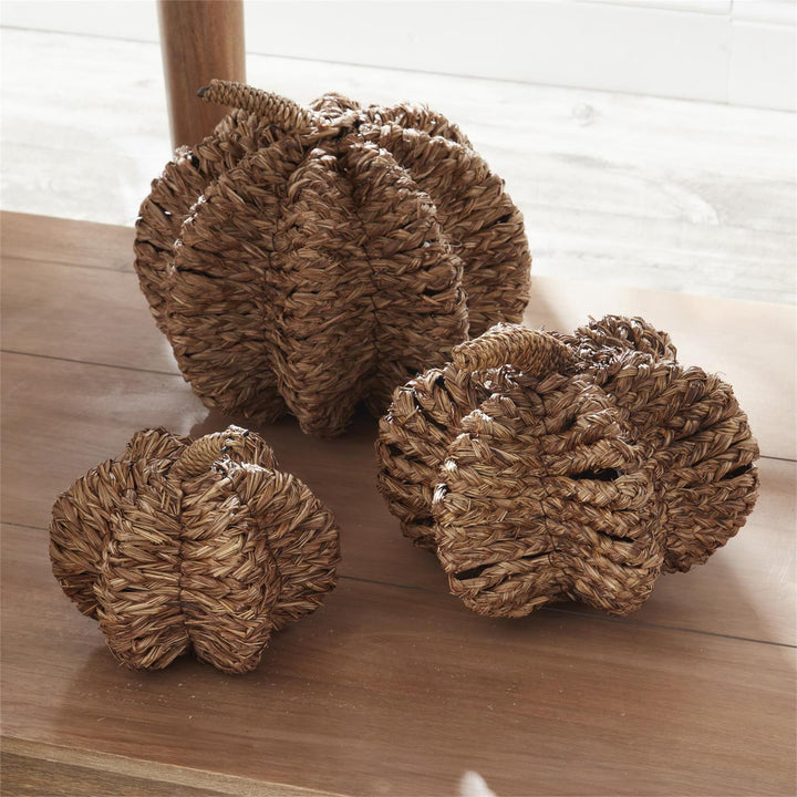 Three woven decorative items on a wooden surface with a blurred background
