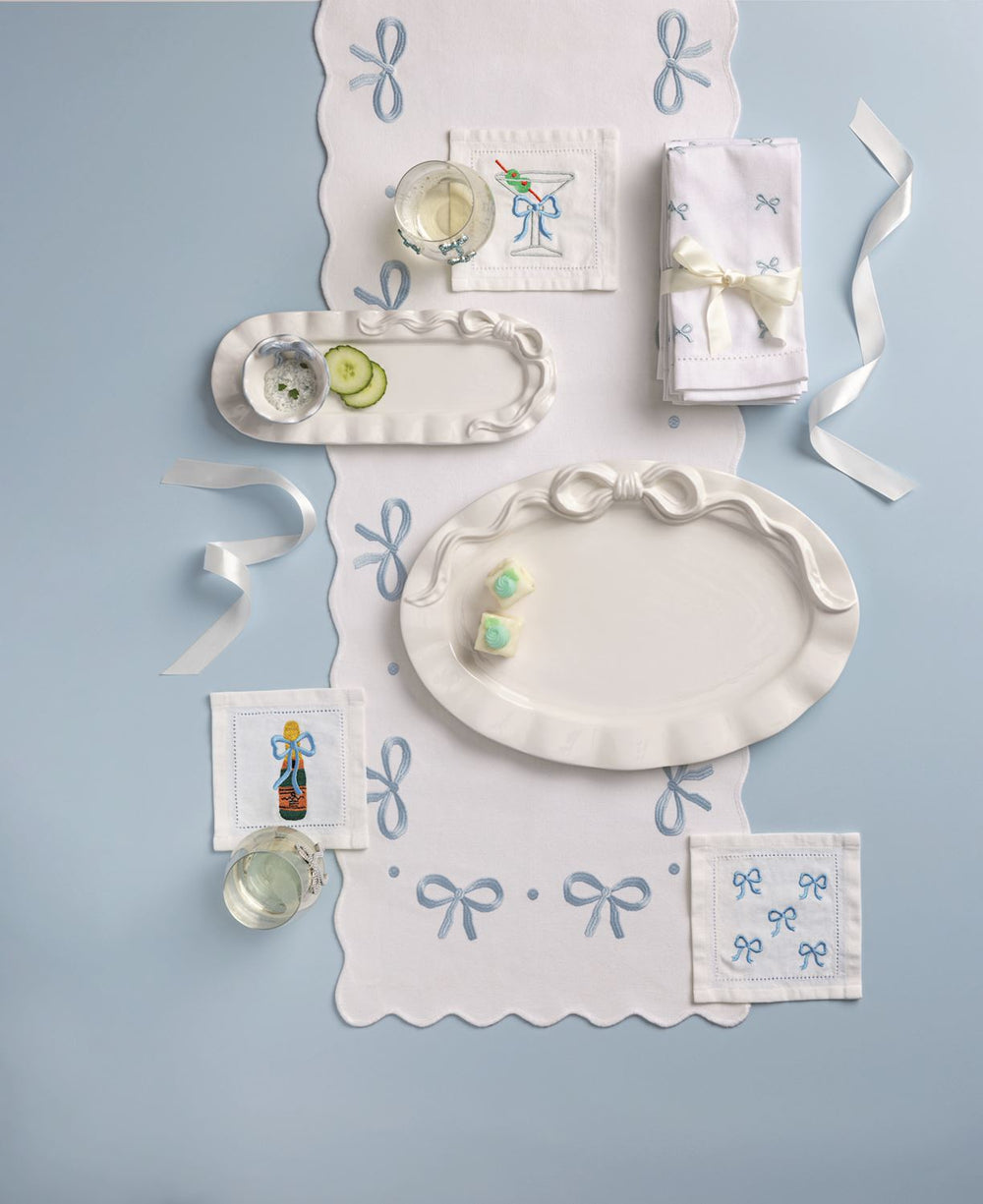 Decorative table setting with white plates, napkins, and small items on a light blue background.