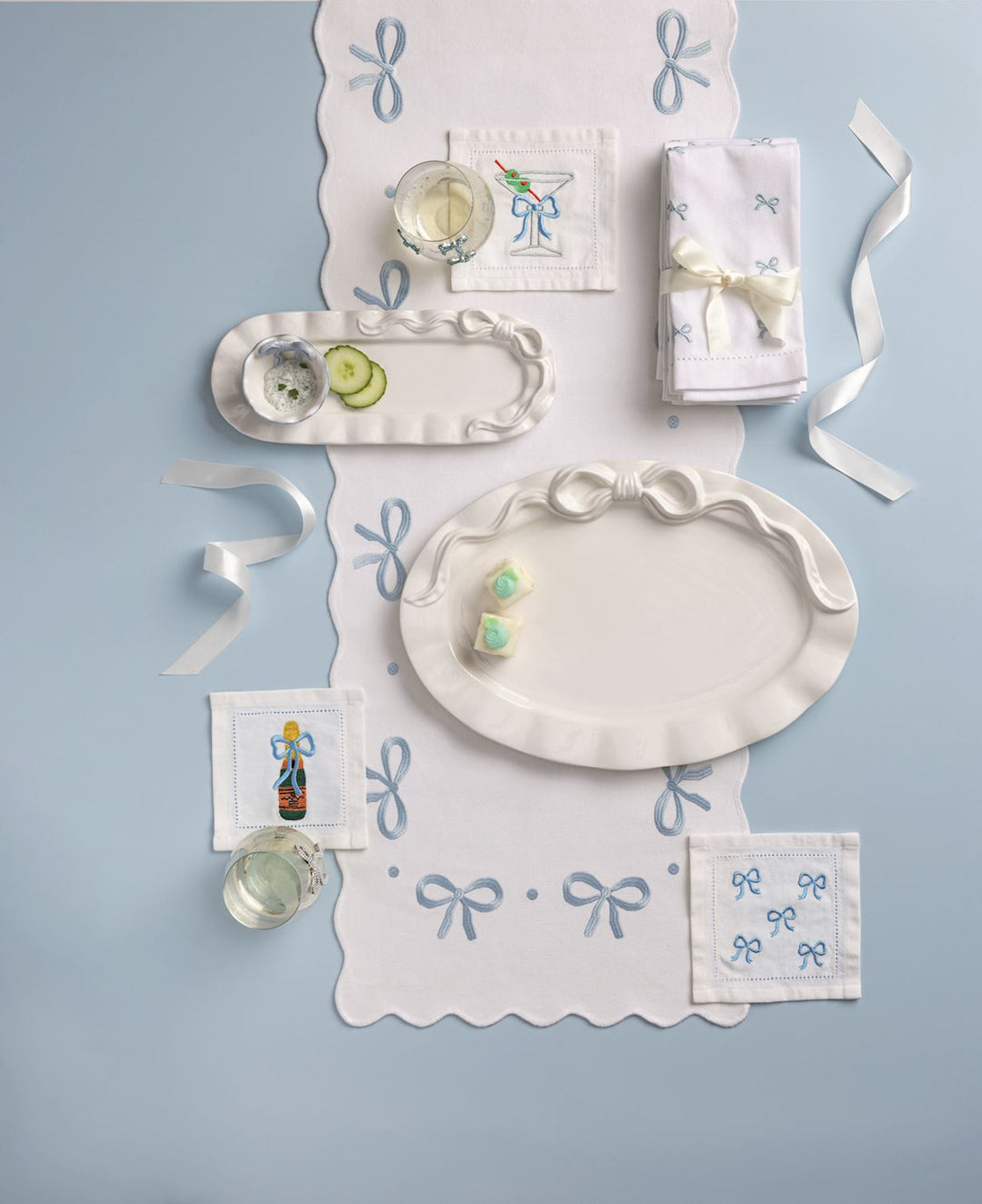 Decorative table setting with white plates, napkins, and small items on a light blue background.