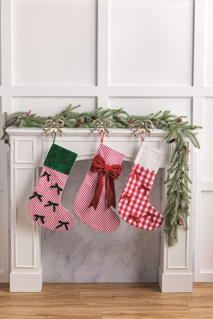 Three Christmas stockings hanging on a fireplace mantel with decorative garland.
