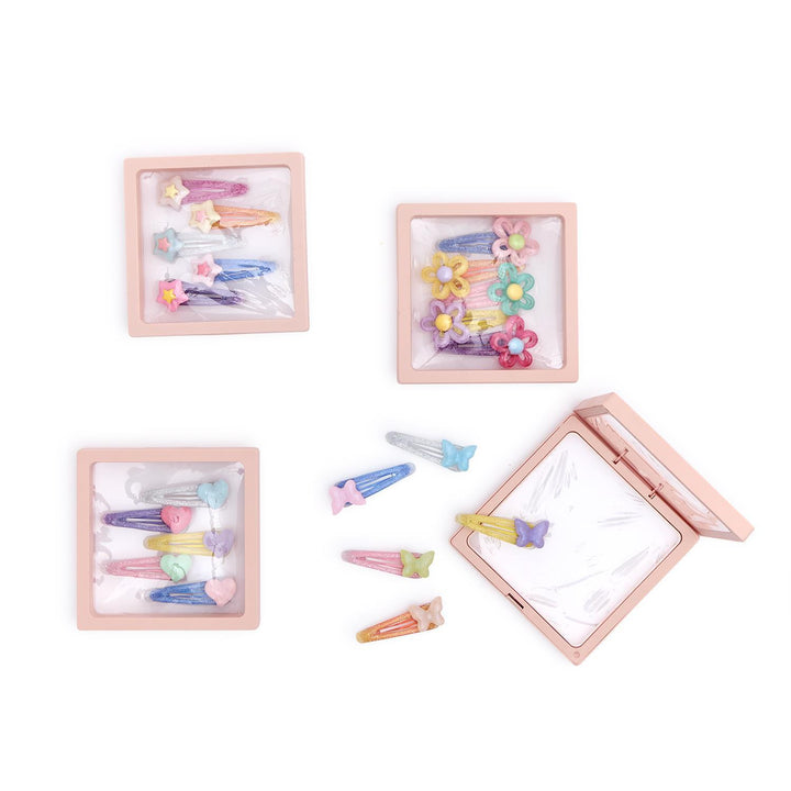 Set of colorful hair clips in a wooden box on a white background