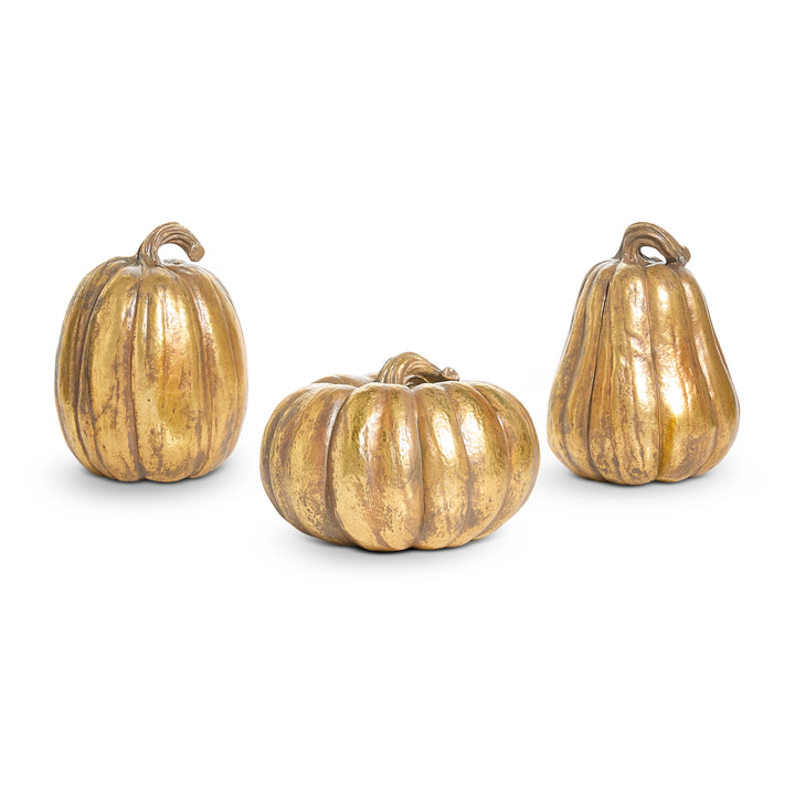 Three decorative pumpkins with a gold finish on a white background