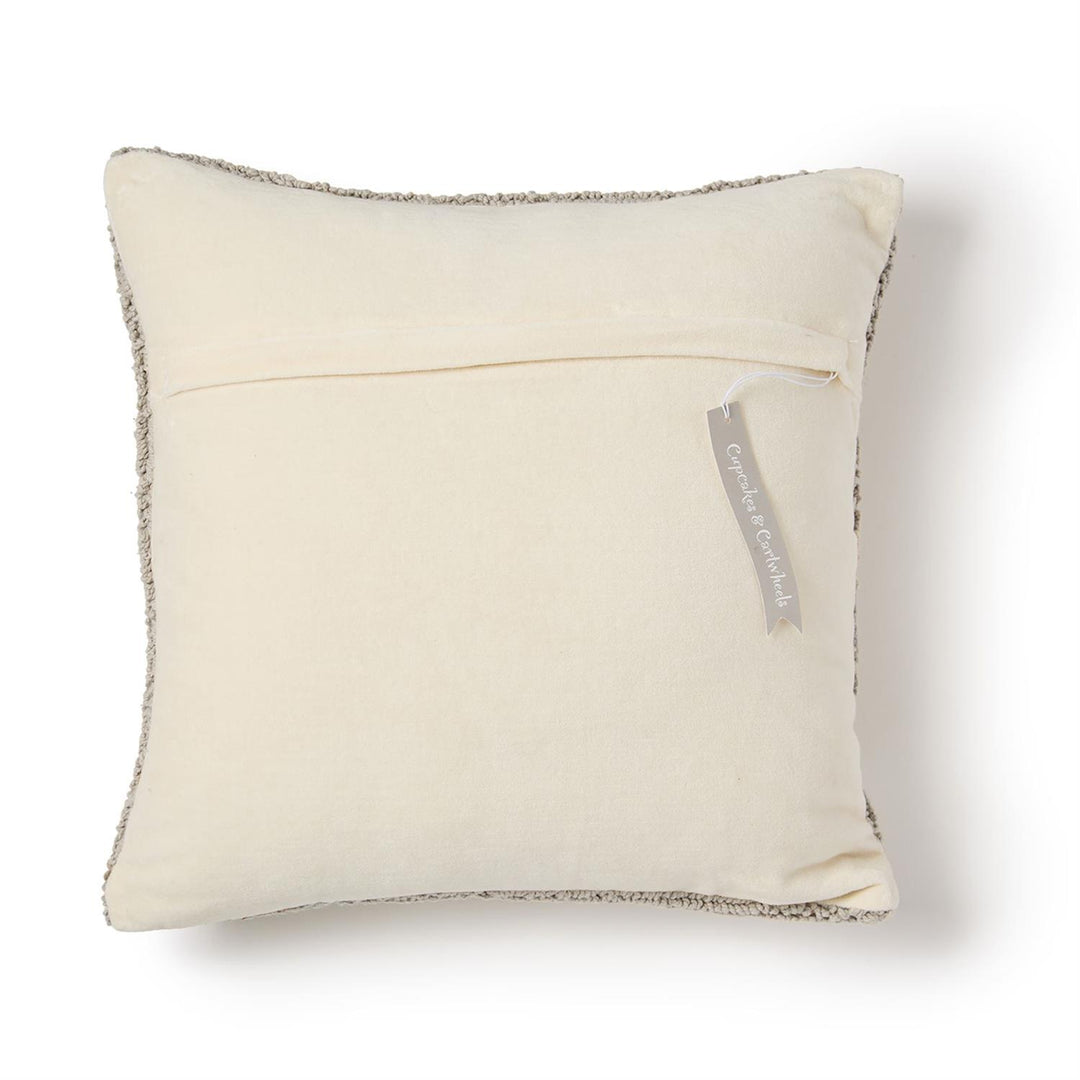 Beige pillow with textured edge and visible brand tag on a white background