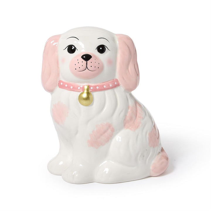Ceramic dog-shaped piggy bank with pink spots and a gold bell on a white background
