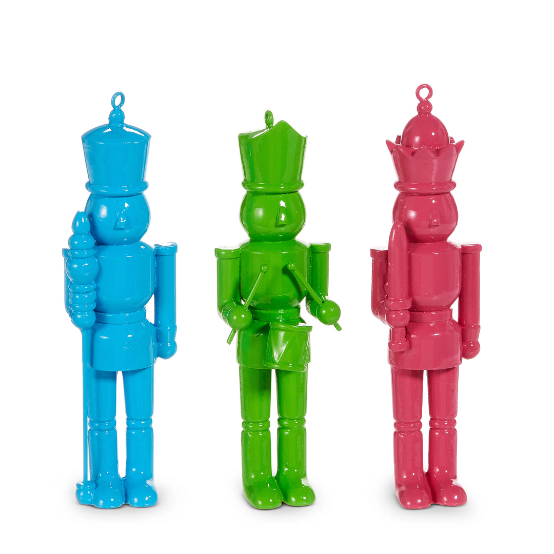 Three colorful toy soldiers in blue, green, and pink on a white background