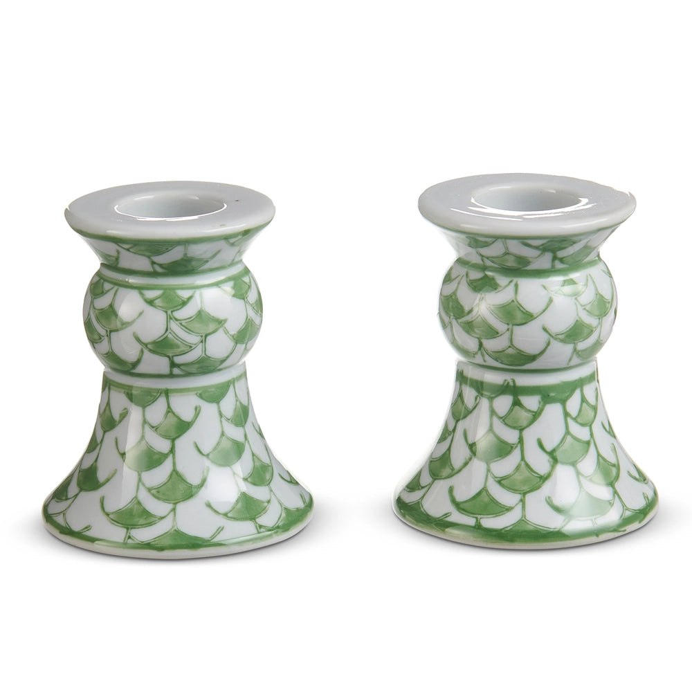 Two green and white patterned candle holders on a white background