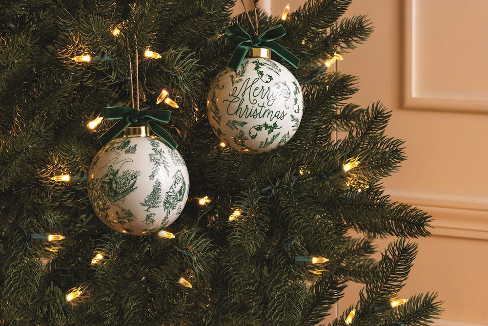 Green toile christmas ornament on lit Christmas tree