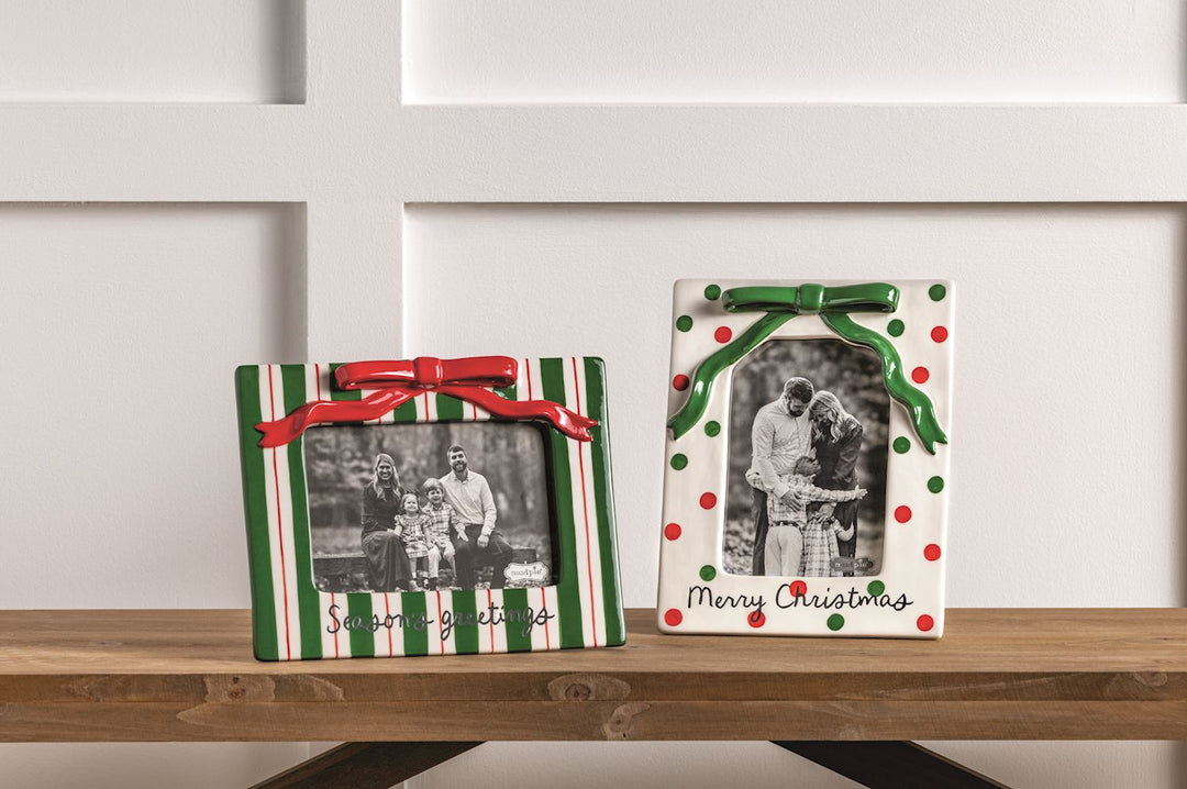 Two decorative picture frames with Christmas designs on a wooden surface.