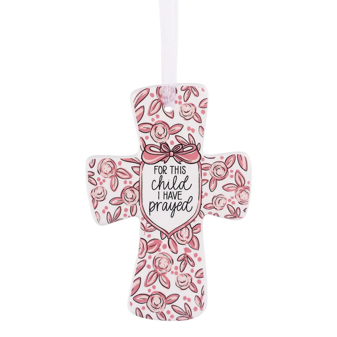 CROSS ORNAMENT WITH PINK FLORAL DESIGN AND "FOR THIS CHILD I HAVE PRAYED" PAINTED ON IT ON WHITE BACKGROUND