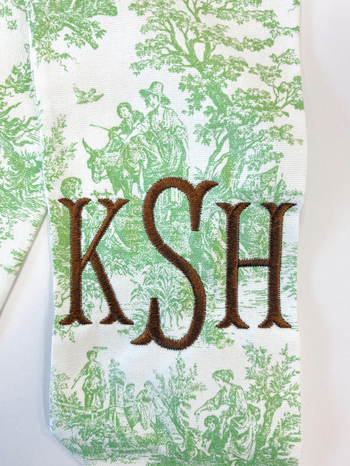 Fabric with green toile pattern and embroidered initials 'KSH'