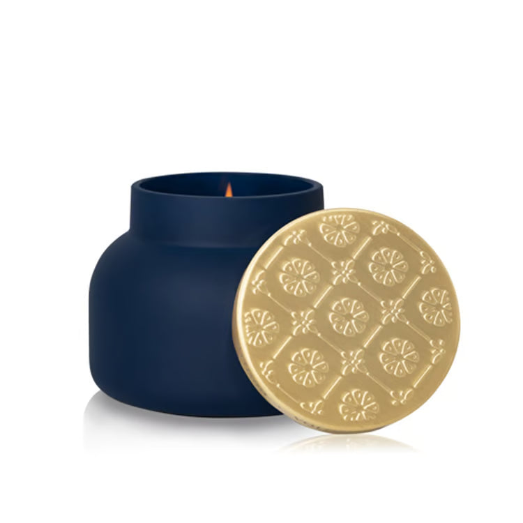Navy blue candle with a gold lid on a white background