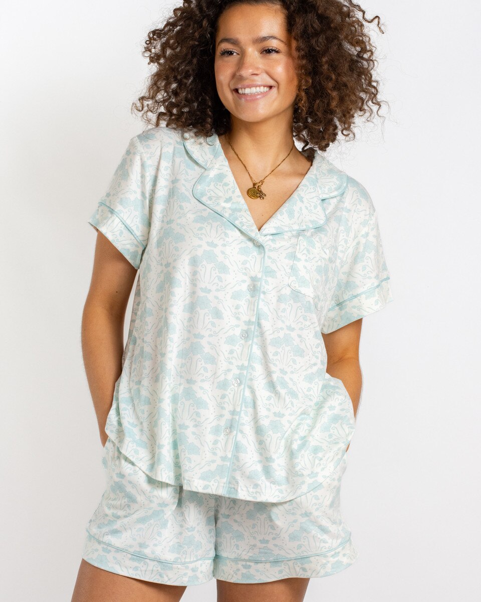 Woman wearing a light blue and white patterned pajama set on a plain background