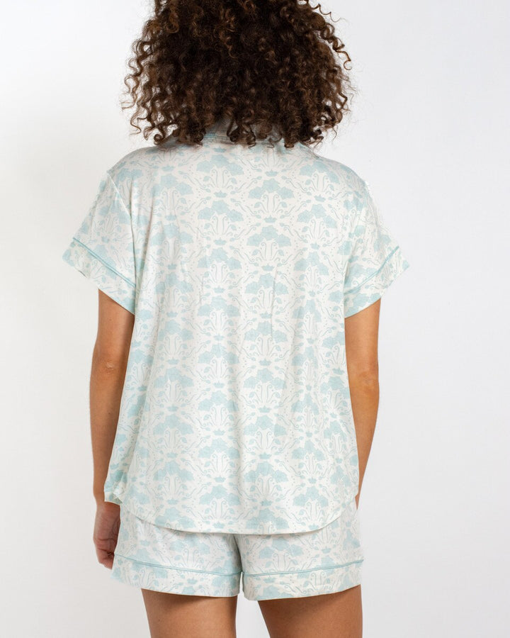 Person wearing a light blue floral pajama set on a white background