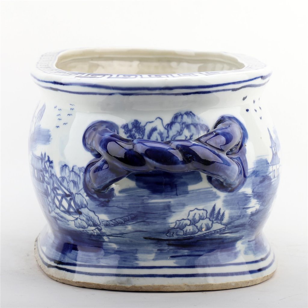Blue and white ceramic pot with landscape design on a white background
