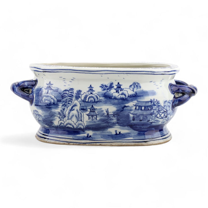 Blue and white ceramic dish with scenic design on a white background