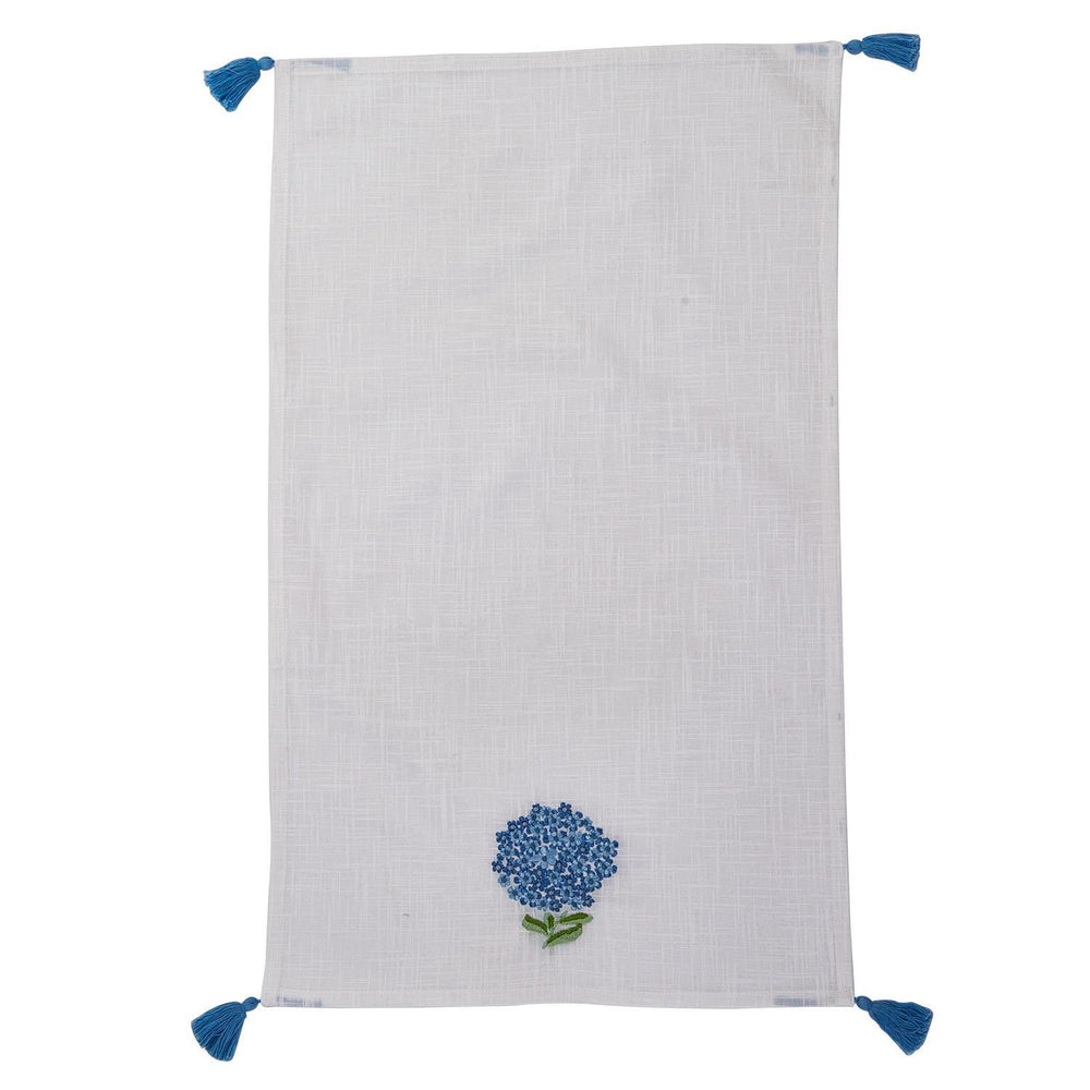 White towel with blue floral embroidery and tassels on a white background