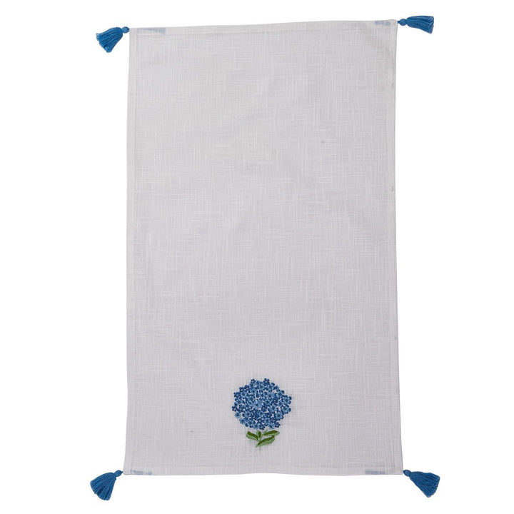 White towel with blue floral embroidery and tassels on a white background