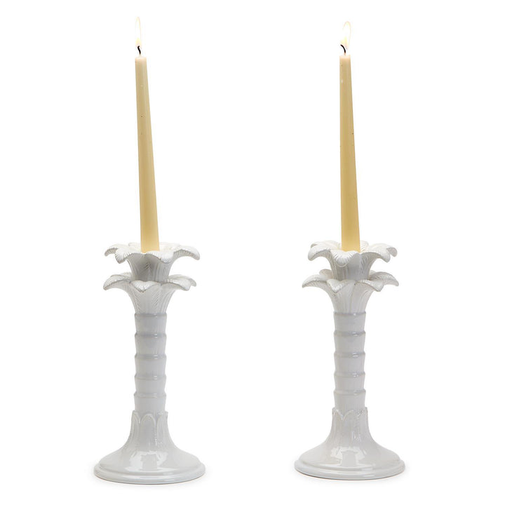 Two white candle holders with candles on a white background