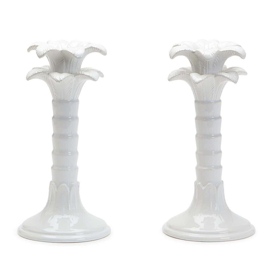 Two white ceramic candle holders with floral designs on a white background