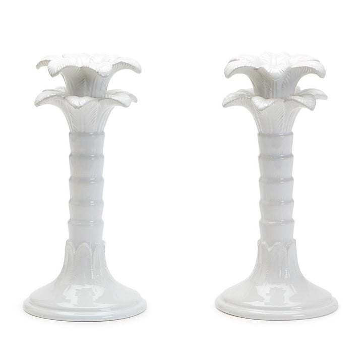 Two white ceramic candle holders with floral designs on a white background