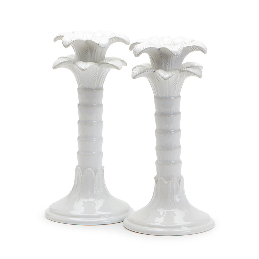 Two white ceramic candle holders with floral designs on a white background