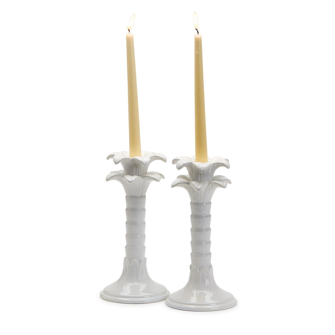 Two white candle holders with candles on a white background