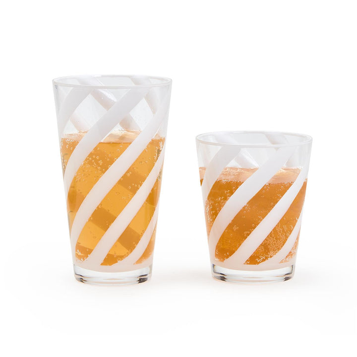Two glasses with orange juice and white swirl patterns on a white background